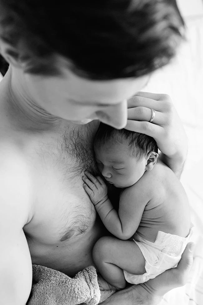 Ein neugeborenes Baby liegt auf dem nackten Oberkörper des Papas, fotografiert im Krankenhaus von Britta Passmann Dortmund